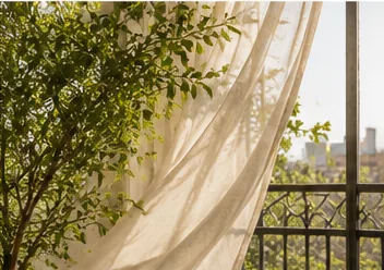 A sheer curtain lifting in an open window, morning light coming through